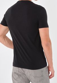 T-shirt nera a maniche corte realizzata in morbido cotone, con scollo rotondo e design aderente. Retro semplice senza loghi visibili.
