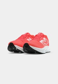 Pair of bright coral running shoes with white midsoles, black rubber outsoles, and large white "N" logos on sides.