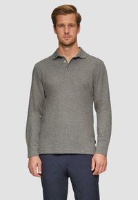 Szary longsleeve polo z kołnierzykiem, dwuprzyciskowym zapięciem i gładką fakturą. Połączony z granatowymi spodniami, zaprezentowany na neutralnym tle.