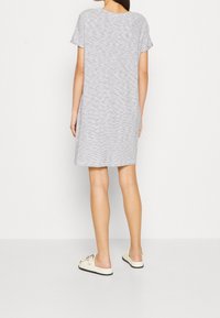 Grå och vit randig kortärmad klänning med avslappnad passform, som når mitt över låret, i kombination med ljusa slip-on skor.