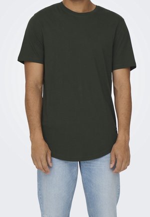 Ciemnozielona bawełniana koszulka z okrągłym dekoltem i krótkimi rękawami, z zaokrąglonym dołem. Noszona z jasnoniebieskimi dżinsami.