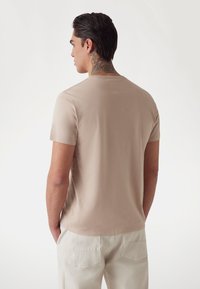 Beige short-sleeve t-shirt made of soft cotton, featuring a crew neckline and a smooth texture, with a plain back and minimal detailing.