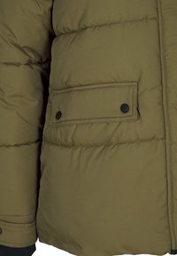 Olive spalvos pūkuota striukė su stačiakampiu kišeniu ir juodais mygtukais, išklota tekstūra ir raukšlėtais rankovėmis, kad būtų šilčiau.