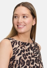 Leopárdmintás, ujjatlan felső puha anyagból, laza szabású, kerek nyakú, barna és fekete kontrasztos mintákkal.