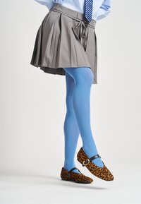 Falda gris con pliegues, medias de color azul claro y zapatos planos de estampado de leopardo con un detalle de correa y hebilla negra. Enfóquese en los colores y las texturas.