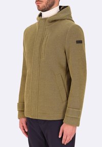 Giacca verde oliva, in tessuto strutturato, con cappuccio, zip frontale e due tasche laterali. Presenta una leggera lucentezza e un accento marrone sulla manica.