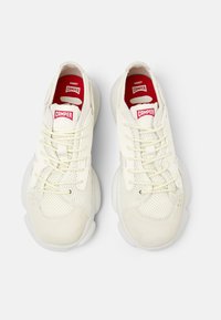 Sneakers bianche con pannelli in mesh e suede, punta tonda, suola spessa e logo rosso Camper sulla linguetta. Design classico con lacci.