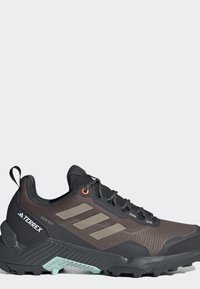 Czarno-brązowy but do biegania w terenie Adidas Terrex z wytrzymałą podeszwą, sznurowanym zapięciem i jasnoniebieskim detalem trakcj na podeszwie.