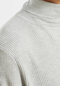 Suéter de cuello alto de punto acanalado en gris claro, con un cuello alto y un patrón texturizado, que ofrece un ajuste ceñido alrededor del cuello y los hombros.