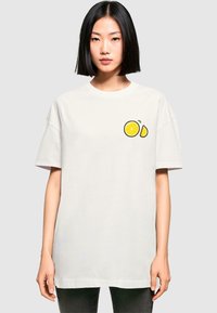 Hvid bomulds t-shirt med grafik af en citron og en skive, korte ærmer, rund halsudskæring og afslappet pasform.