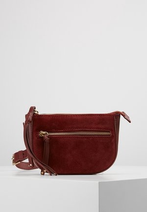 Sac bandoulière en suède bordeaux avec une finition en cuir, doté d'une poche zippée à l'avant et d'une sangle ajustable. Matériel de fermeture éclair en or lisse.