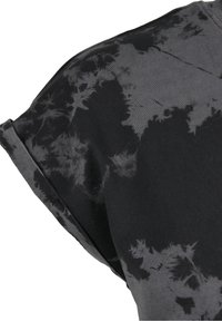 Tissu à manches courtes tie-dye noir et gris foncé avec un revers plié sur la manche, montrant une texture douce en coton.