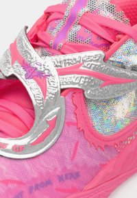Růžová teniska s texturovaným povrchem, lesklými stříbrnými akcenty a pevně padnoucím designem. Obsahuje výrazné fialové a reflexní detaily s výraznou grafikou.