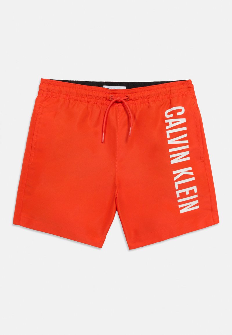 Helle orangefarbene Badeshorts mit Seitentaschen, verstellbarem Kordelzug in der Taille und weißem, vertikal verlaufendem "Calvin Klein"-Logo am rechten Bein.