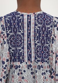 Blaues Blumenkleid mit aufwendiger Stickerei am Oberteil und den Ärmeln. Es zeichnet sich durch verschiedene Blumenmuster und einen weichen, leichten Stoff aus.