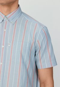 Kurzärmliges Hemd zum Knöpfen in Hellblau mit roten und weißen vertikalen Streifen. Verfügt über eine Brusttasche und einen spitzen Kragen.