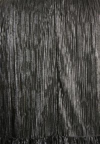 Černá skládací látka se lesklými metalickými pruhy, která má na spodním okraji nařasený lem pro zvýšení textury a detailu.