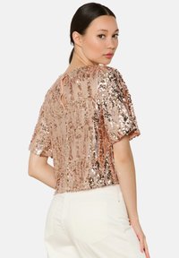 Short-sleeved, rose gold sequined top with a textured pattern. Features a round neckline and a small back keyhole opening.