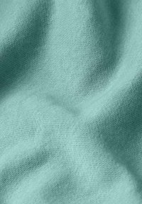 Tissu doux de couleur bleu sarcelle claire avec une texture finement tissée et des plis délicats créant des ombres et des reflets subtils.