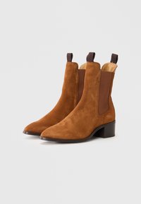 Brązowe zamszowe botki za kostkę z szpiczastym noskiem, elastycznymi bocznymi panelami i niskim blokowym obcasem, z gładką podszewką wewnętrzną.