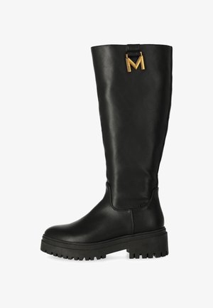 Botas negras hasta la rodilla hechas de cuero suave, con suela gruesa y un acento dorado en forma de "M" en la parte superior.