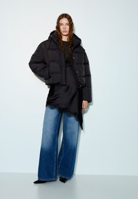 Veste matelassée noire au design court, associée à une robe en satin noir ornée de dentelle et à un jean en denim bleu à jambes larges.