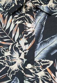 Μαύρο πουκάμισο με κοντά μανίκια και λευκά λουλουδένια και φυλλώδη σχέδια, με λευκά κουμπιά και κλασικό γιακά. Μαλακό ύφασμα με λεπτομερείς ραφές.