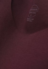 Burgundowa bawełniana koszulka z dekoltem w serek. Posiada metkę "Superior Cotton", rozmiar S, zaprojektowana we Włoszech, wyprodukowana w Serbii.