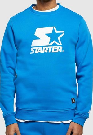 Sudadera azul hecha de mezcla de algodón, con logo blanco "STARTER" y diseño de estrella en la parte frontal. Puños acanalados y dobladillo con etiqueta de logo en la parte inferior.