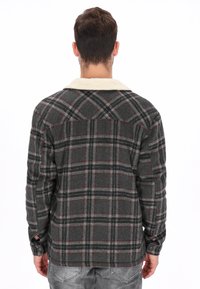 Camisa de franela a cuadros grises con cuello de borrego en crema. Presenta puños con botones y un ajuste relajado, mostrando un patrón clásico de cuadros.