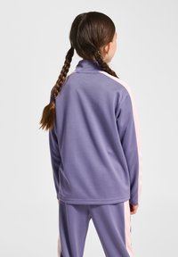 Paarse fleecejas met een hoge kraag, roze zijpanelen en een gladde textuur, gecombineerd met een bijpassende broek.