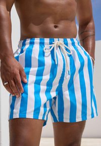 Blaue und weiße gestreifte Badeshorts aus leichtem Stoff, mit einem elastischen Bund und einem Kordelzug sowie Seitentaschen.