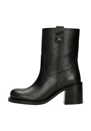 Botte de cheville en cuir noir avec un bout arrondi, un talon carré et des coutures latérales. Équipée d'une languette à l'arrière et d'un détail de marque subtil.