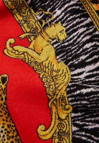 Yellow lion and leopard motifs within ornate gold scrollwork on red and black zebra-striped fabric background.