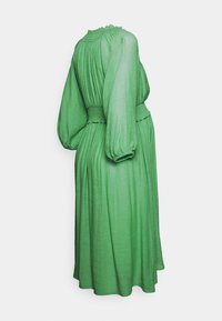 Vestuário verde de mangas compridas feito de um tecido leve e texturizado. Apresenta um decote drapeado, cintura elástica e saia fluida.