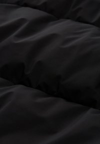 Juodas siuvinėtas audinys, turintis lygų tekstūrą, su švelniu blizgesiu. Paviršiuje matyti subtilūs bangavimai ir klostės, su tolygiai išdėstytais iškilimais.