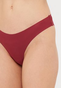 Burgundy bikinitrosor med sömlösa kanter, minimal täckning och en mjuk textur. Designade för en nära passform och komfort.