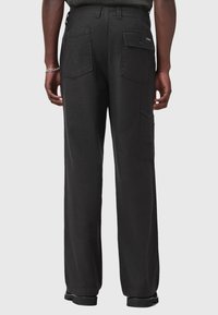 Pantaloni cargo neri con una vestibilità rilassata, grandi tasche posteriori, tasche cargo laterali e una texture liscia. Presentano passanti per cintura e un branding discreto.