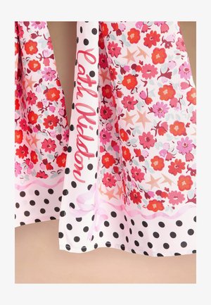 Pink and red floral dress hem with black polka dot border and "Patta Oldsp" script text on white fabric.