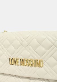 Borsa in pelle bianca trapuntata con logo "LOVE MOSCHINO" in tono oro. La chiusura con zip e il sottile dettaglio di cuciture arricchiscono il design.