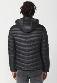 Padded black jacket with a hood, featuring horizontal quilting, a smooth texture, and a front zipper, positioned against a plain background.
