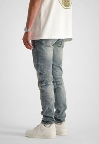 Bleka blå skinny jeans med en lätt stretch, med fem fickor och synliga sömmar, i kombination med vita sneakers.