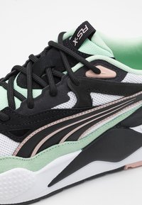 Schwarze und mintgrüne Sneaker mit einem Obermaterial aus Mesh, komplexem Design, gepolsterter Schuhkragen und einer strukturierten Gummisohle mit kontrastierenden Akzenten.