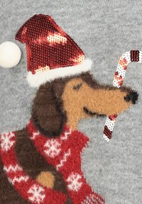 Dog wearing a red sequined Santa hat and red sweater with white snowflakes, holding a candy cane against a gray background.