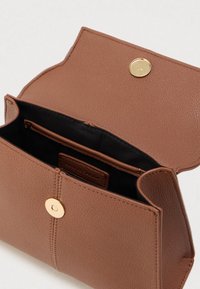 Καφέ δερμάτινη τσάντα με υφή, εξοπλισμένη με χρυσό κούμπωμα και μαύρο εσωτερικό με επιπλέον θήκη.