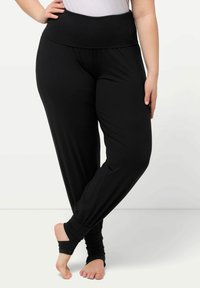 Pantalones de yoga negros, ligeros, con una cinturilla ancha, piernas ajustadas y puños fruncidos en los tobillos, que presentan una textura suave y elástica.