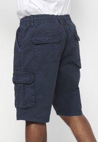 Férfi tengerészkék cargo sortot visel, amely több zsebbel és elasztikus derékkal rendelkezik, hátulról és oldalról bemutatva.