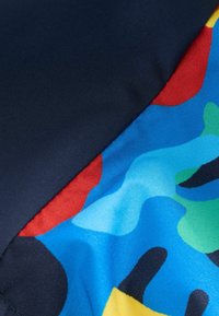 Schwimmanzugstoff mit einem navyblauen Abschnitt und einem bunten, abstracten Muster aus blauen, roten, grünen und schwarzen Formen; glatte Textur.