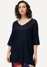 Marineblauer Strickoberteil mit V-Ausschnitt, kurzen Ärmeln und lockerer Passform, aus strukturiertem Stoff mit seitlichen Schlitzen für mehr Bewegungsfreiheit.