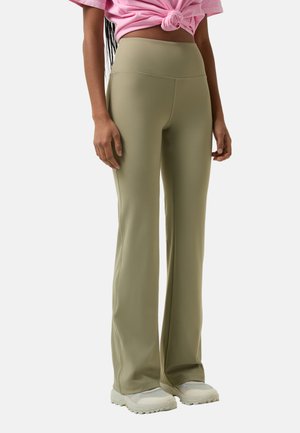 Fitted olive green flared pants with a high waist, smooth texture, and stitching details, paired with light-colored athletic shoes.